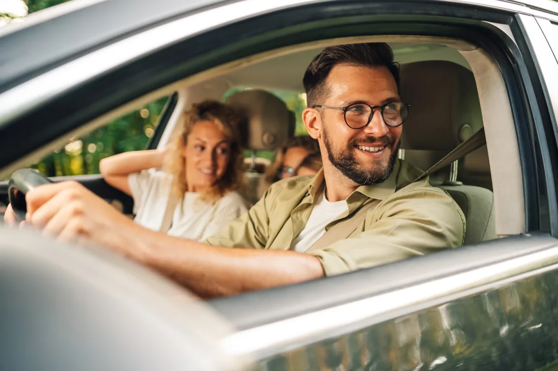 Conductor sonriente con pasajeros dentro de un automóvil
