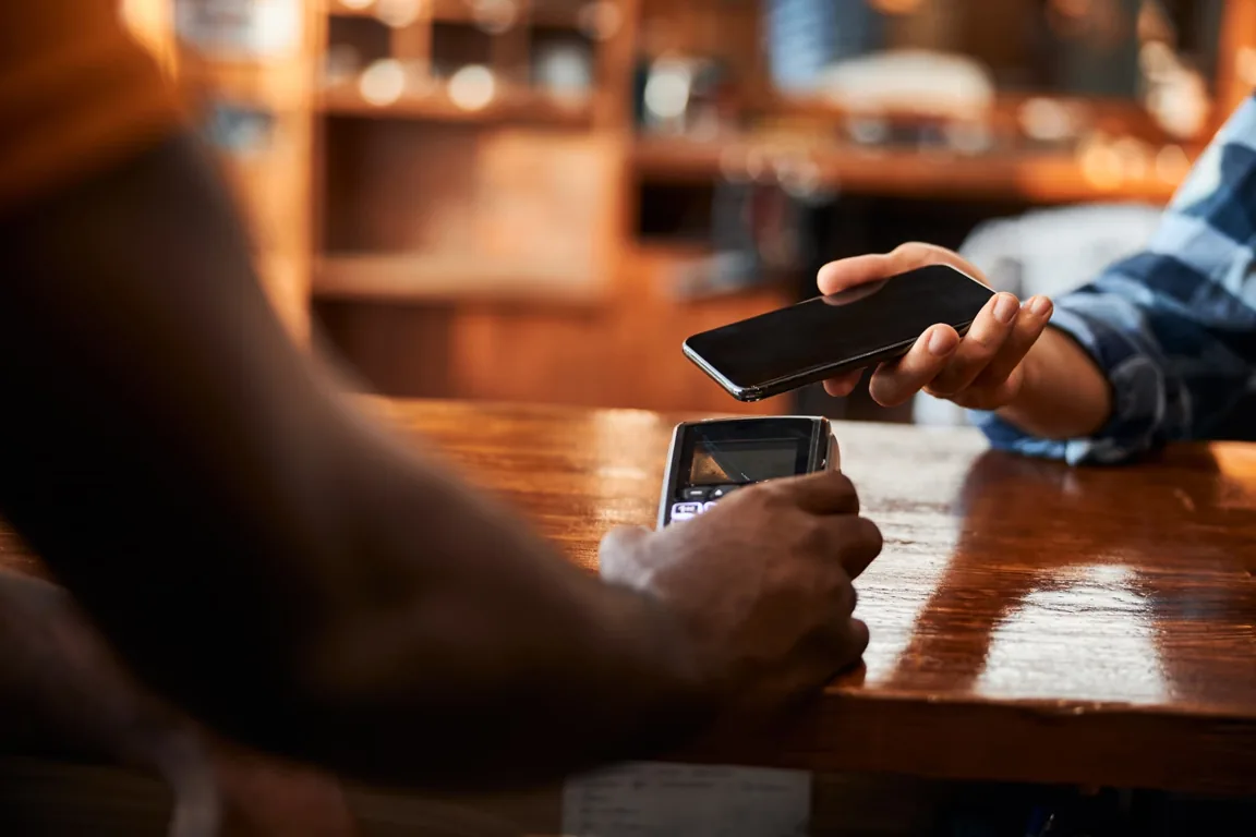 Cliente acercando su celular al datáfono de un comercio